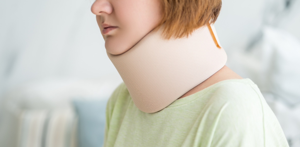 Woman wearing a beige neck brace looks to the side, sitting in a bright indoor setting