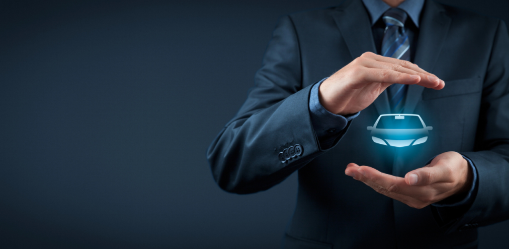 A man in a suit holding his hands around a glowing car symbol, representing car insurance protection