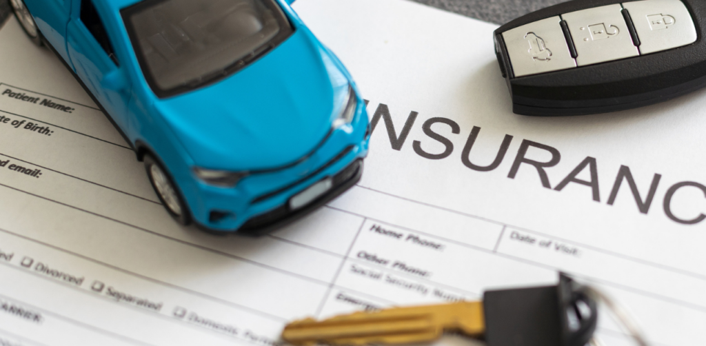 Close-up of a toy car, car keys, and an insurance document, emphasizing vehicle insurance or related paperwork