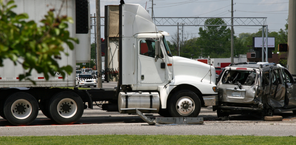 White semi-truck and a heavily damaged SUV after a collision at an intersection, with debris scattered on the road