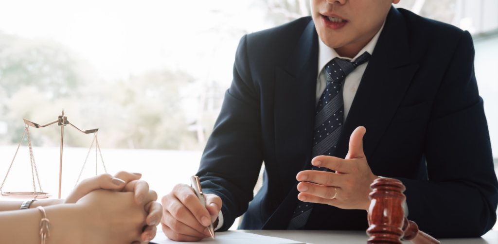 Lawyer discusses personal injury claim with client, gavel and justice scales on desk
