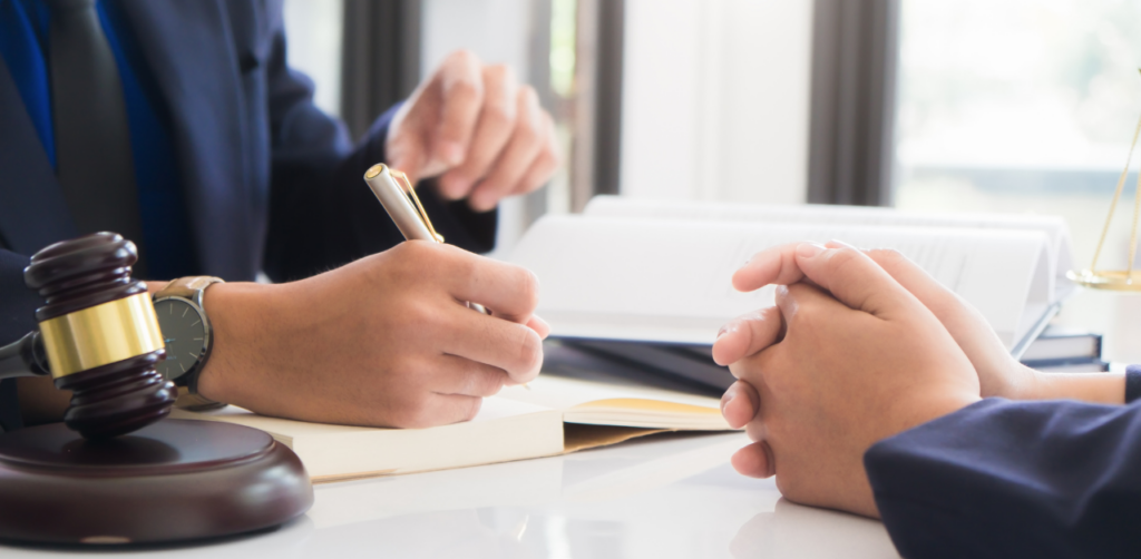 Lawyer writing notes during a legal consultation, with gavel and law books on the desk in front of a client