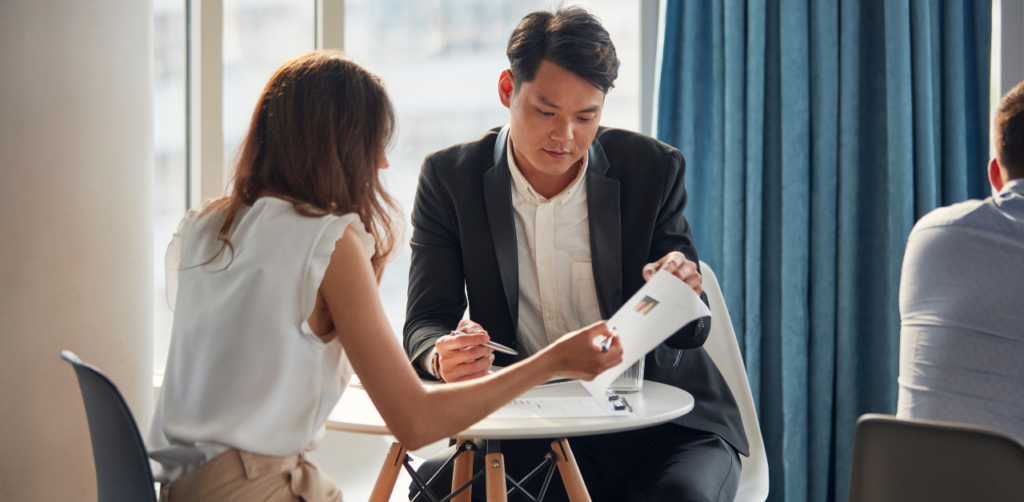 Man and woman reviewing documents in an office meeting, discussing legal assistance options or contract details