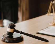 Judge’s gavel on desk beside legal documents and scales of justice in law office