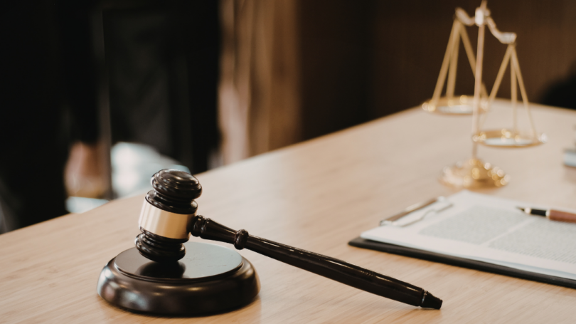 Judge’s gavel on desk beside legal documents and scales of justice in law office