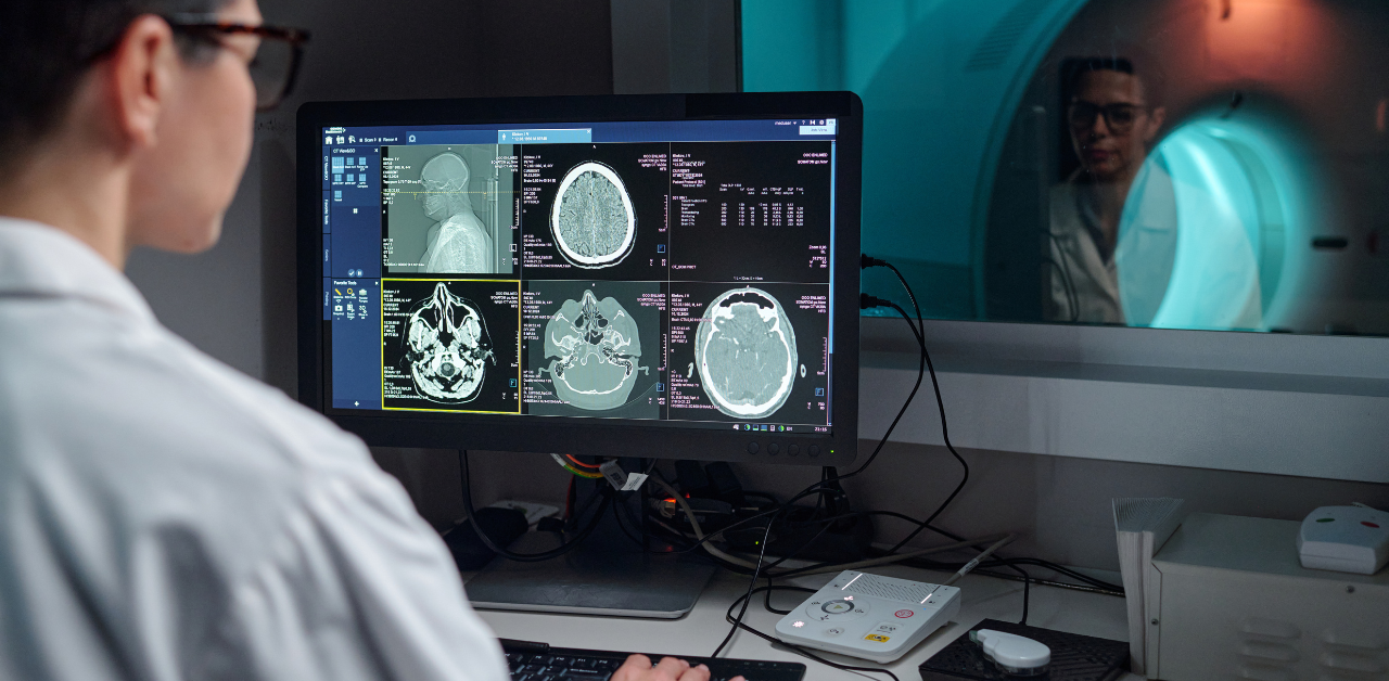 Doctor reviewing brain scan images on computer beside MRI machine, representing medical imaging, diagnostics, and healthcare analysis