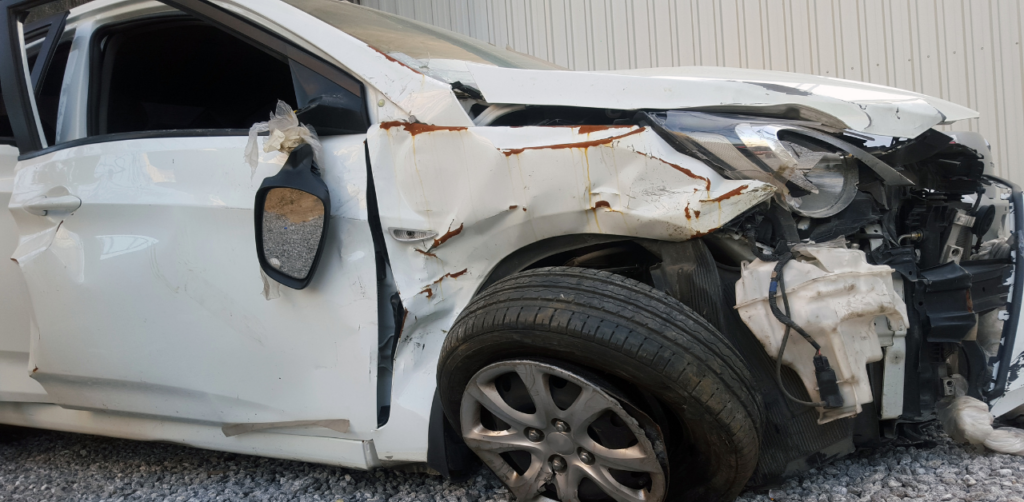 Damaged white car with crushed front end, illustrating injury risk tied to Casino Escalator Accident Claims
