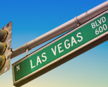 Green street sign reading “N Las Vegas Blvd 600” mounted beside a traffic signal against a clear blue sky