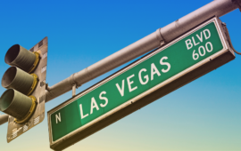 Green street sign reading “N Las Vegas Blvd 600” mounted beside a traffic signal against a clear blue sky