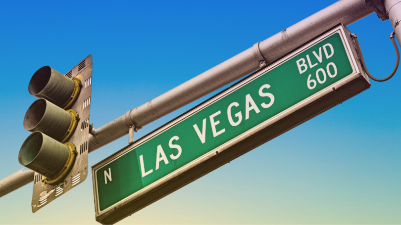 Green street sign reading “N Las Vegas Blvd 600” mounted beside a traffic signal against a clear blue sky