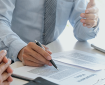 Insurance representative reviewing policy documents with a client at a desk, pointing to paperwork during a discussion about coverage or claims