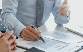 Insurance representative reviewing policy documents with a client at a desk, pointing to paperwork during a discussion about coverage or claims