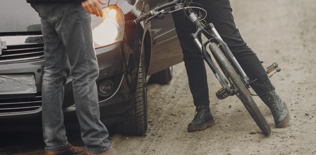 Driver and cyclist stand beside a car and bicycle after a minor collision