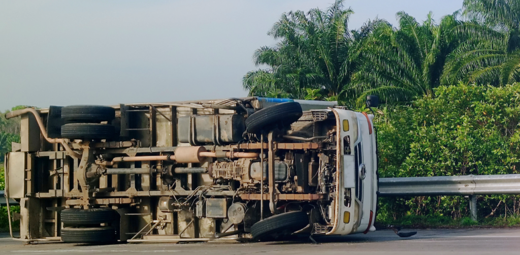 Overturned truck lies on its side beside a highway guardrail