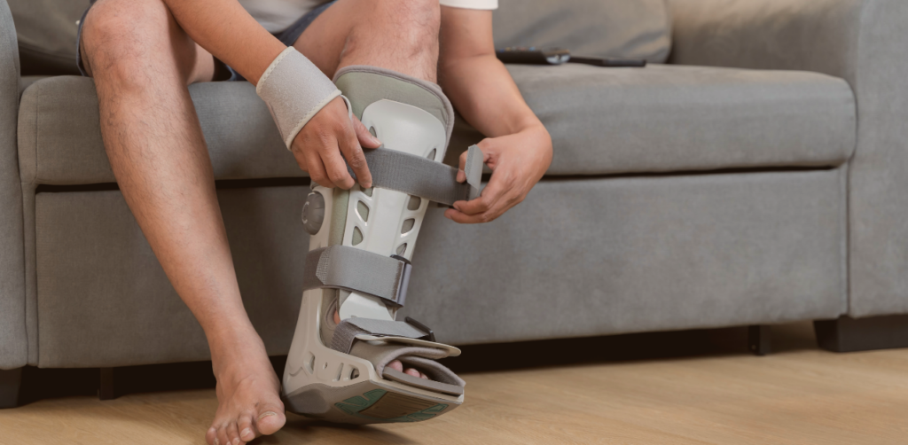 Person fastens a walking boot while recovering from a lower leg or ankle injury