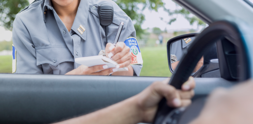 Police officer writes a traffic citation while speaking with a driver