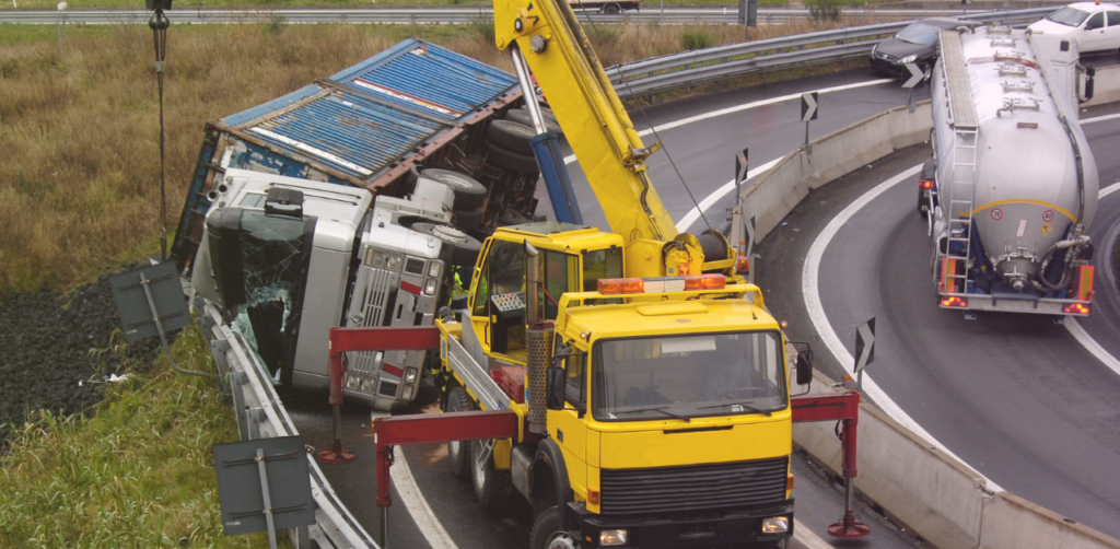 Recovery crews remove an overturned truck from the roadside with a crane