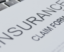 Close-up of an insurance claim form with a pen and computer keyboard in the background
