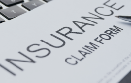 Close-up of an insurance claim form with a pen and computer keyboard in the background