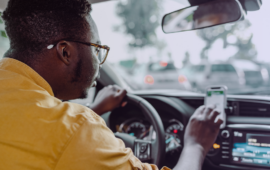Driver holds a smartphone while behind the wheel in slow-moving traffic
