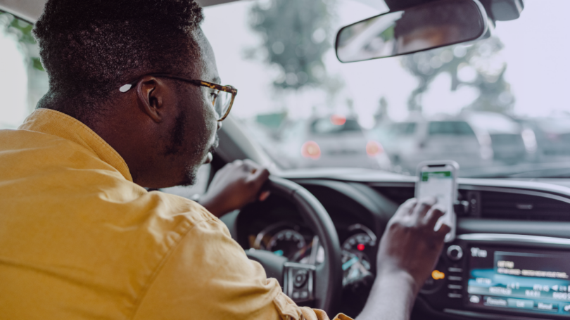 Driver holds a smartphone while behind the wheel in slow-moving traffic